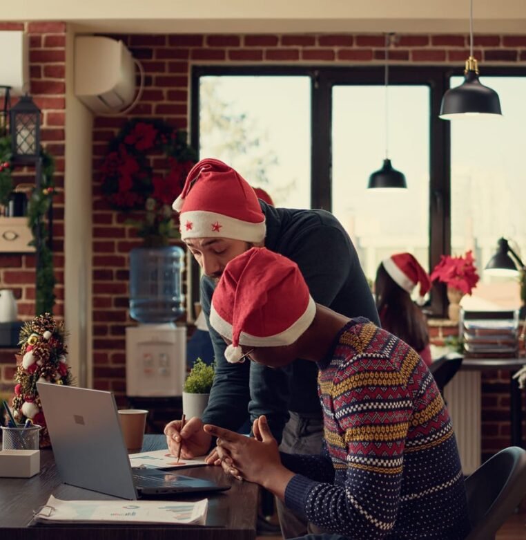multiethnic-team-colleagues-working-laptop-corporate-office-decorated-with-christmas-tree-lights-diverse-men-doing-teamwork-startup-report-xmas-winter-holiday-1